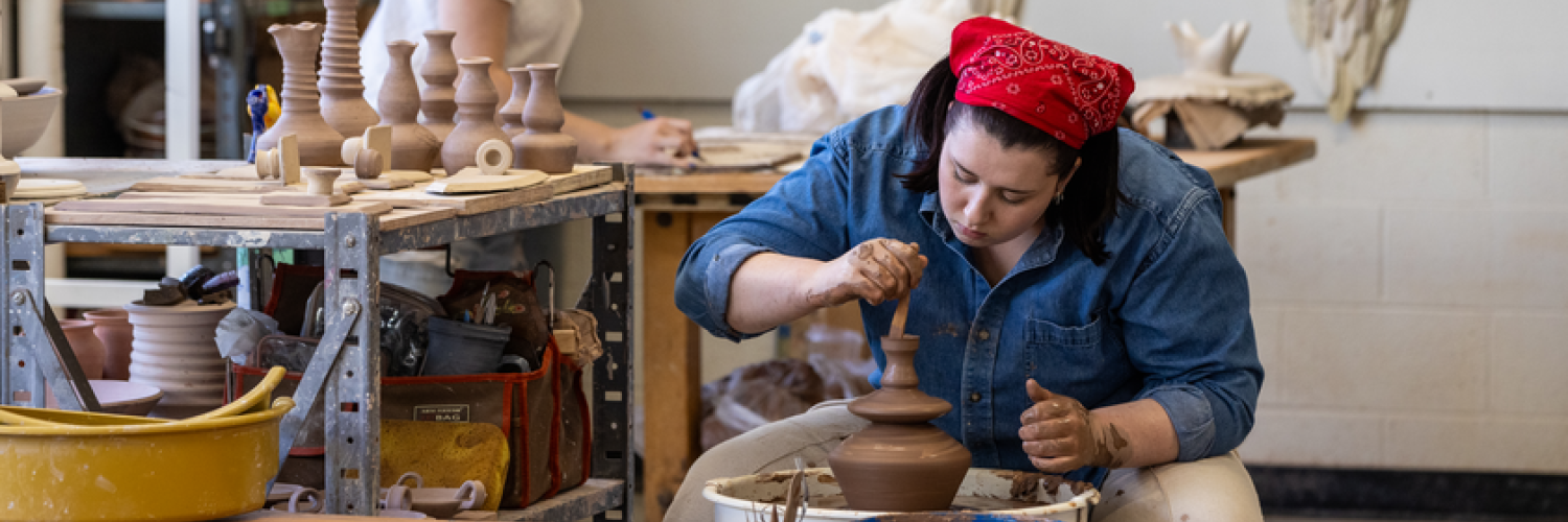A photo of a ceramics student crafting pottery