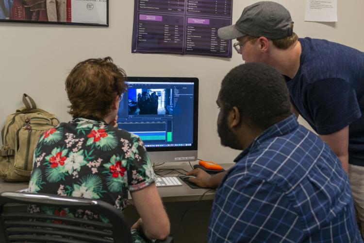 A photo of students looking at a computer