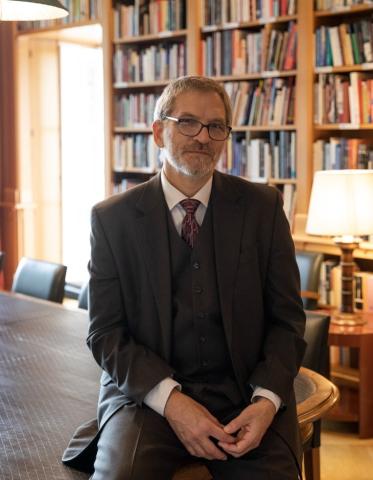 James A. van Dyke sitting on a table in front of a wall of books and a lamp