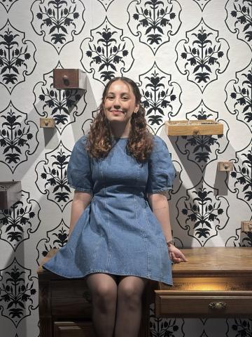 Hanieh Darvishian seated on a dresser in front of a patterned wall
