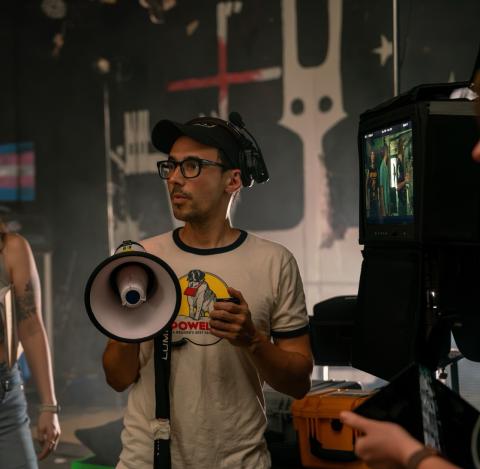 Brian Macneel on a film set holding a megaphone and wearing a headset