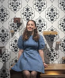 Hanieh Darvishian seated on a dresser in front of a patterned wall