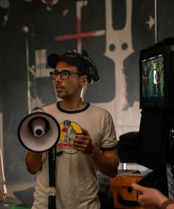 Brian Macneel on a film set holding a megaphone and wearing a headset
