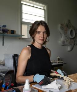 Headshot of Kenzie Wells carving wood in their home studio in Columbia, MO.